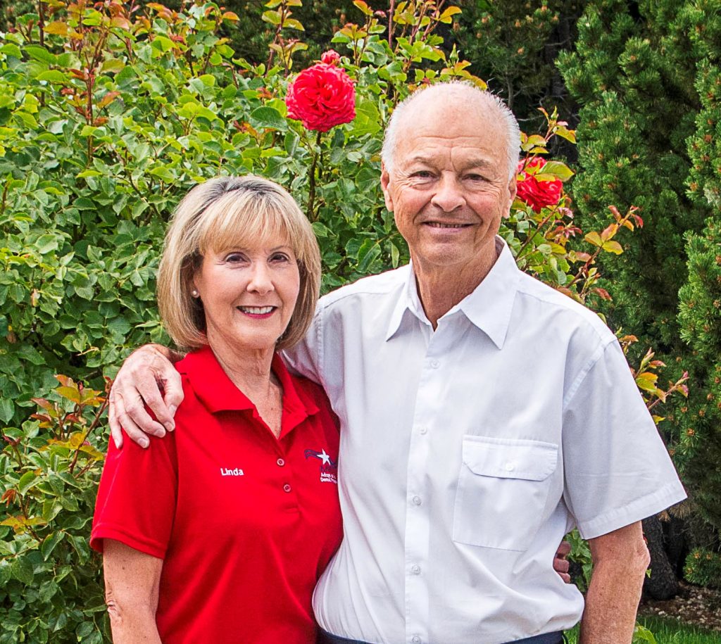 Photo of Wayne and Linda Haigh in Front of a Rose Bush